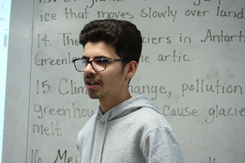 A student standing in front of a white board with writing